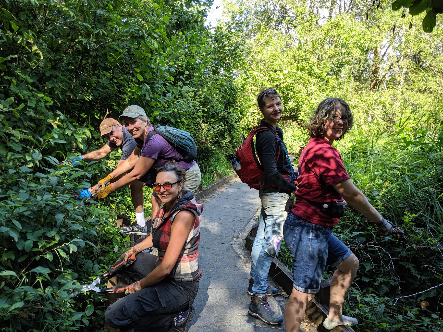 Volunteer trimming plants away from walking trail at McLane Creek